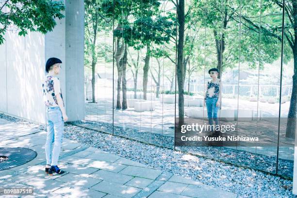 a woman standing in front of a mirror - adult in mirror stock-fotos und bilder