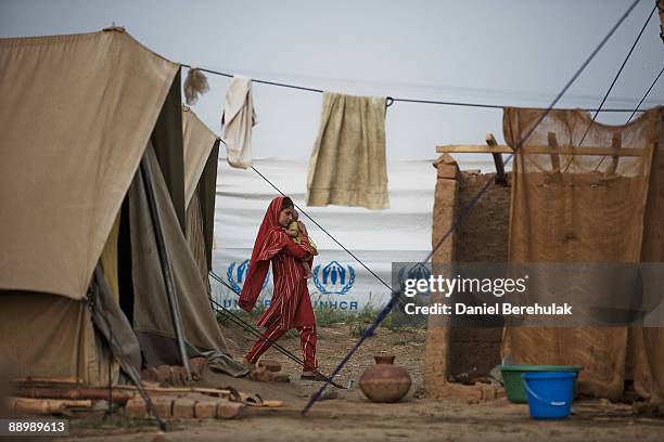 Young Pakistani girl internally displaced from Swat,caries her younger sister at the Yar Hussain UNHCR camp in Chota Lahore on July 12, 2009 in Swabi...