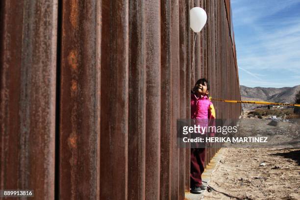 Little girl holds a white ballon at the border wall between Mexico and the United States, during the "Keep our dream alive" event, in Ciudad Juarez,...