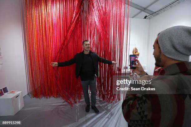 Sasha Gjorsovski poses with an installation titled 'The Sun Has Burnt the Sky' by Anne Patterson on exhibit at Scope Art Fair during Art Basel Miami...