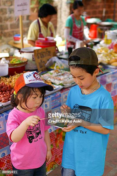 kids eating fried quail's eggs. - chiang mai sunday market stock pictures, royalty-free photos & images