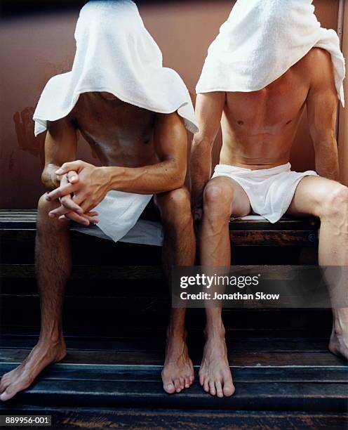 two men in sauna, heads covered in towels - bromance stock-fotos und bilder