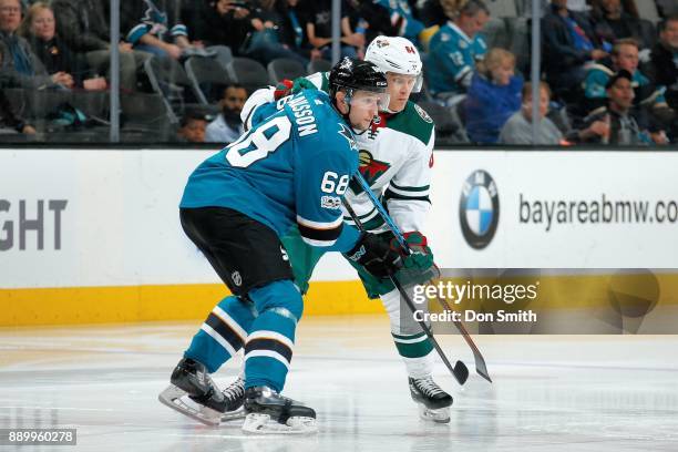 Melker Karlsson of the San Jose Sharks and Mikael Granlund of the Minnesota Wild jostle for position at SAP Center on December 10, 2017 in San Jose,...