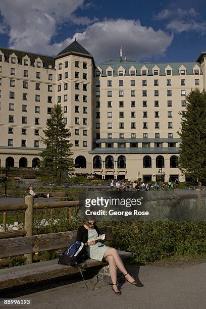 Woman reads a book on a park bench outside the Fairmont Chateau Hotel in this 2009 Lake Louise, Canada, summer afternoon landscape photo.