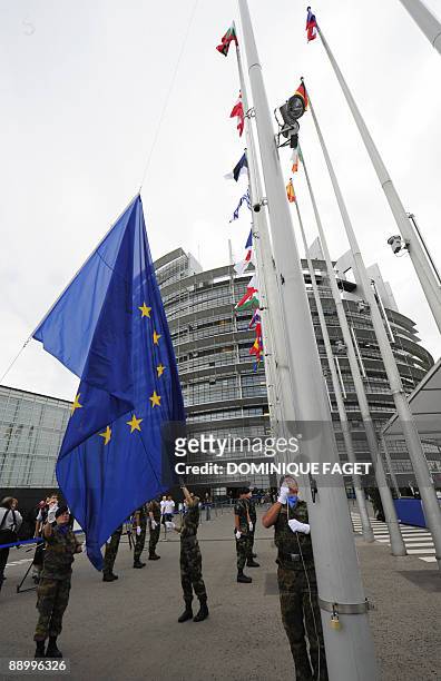 Soldiers of the Eurocorps detachment raise European Union flags to mark the inaugural European Parliament session on July 13 in front of the European...
