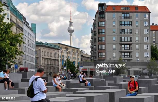 Tourists sit on the concrete steles of the Holocaust memorial in Berlin as the landmark TV tower can be seen in the background on July 13, 2009. The...