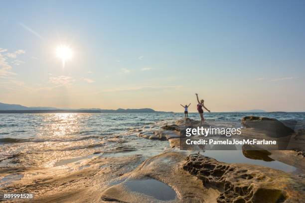 two women embracing nature with arms outsretched on remote beach - british columbia beach stock pictures, royalty-free photos & images