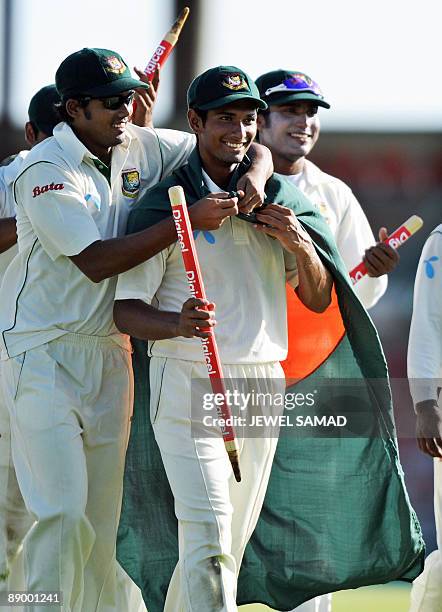 Bangladeshi cricketer Mahmudullah is adorned with a national flag by his teammates following their victory at the end of the final day of the first...