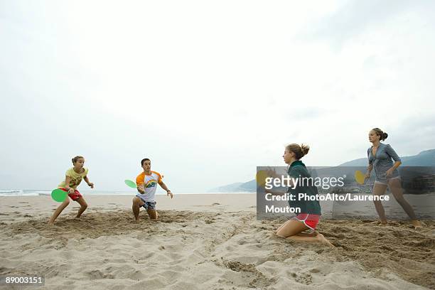 teen friends playing paddleball on beach - teen boy shorts stockfoto's en -beelden