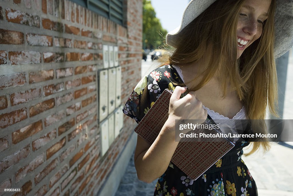 Young woman carrying notebook, smiling and looking down