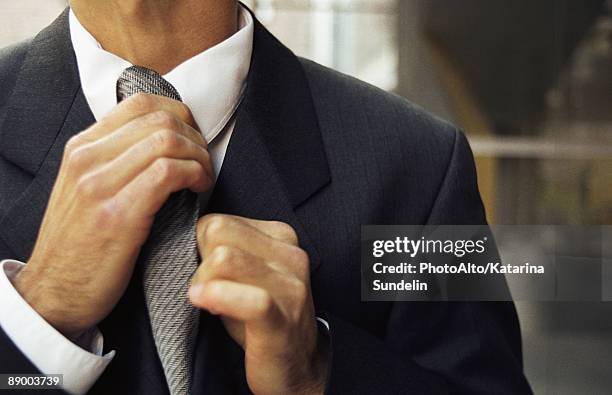 man adjusting tie, cropped - abrigo negro fotografías e imágenes de stock