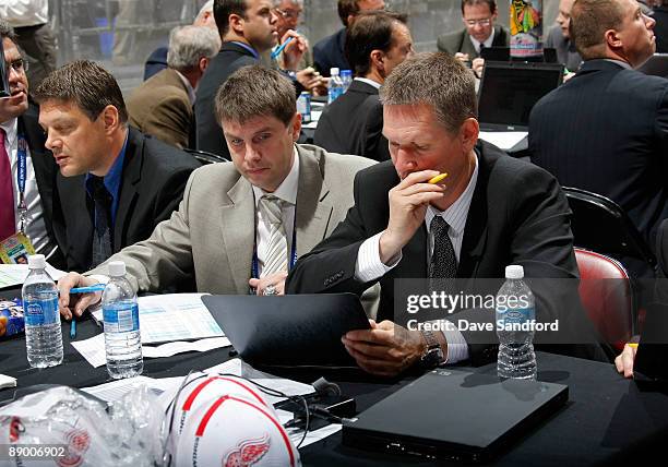 Hakan Andersson, Evgeni Erfilov and Ari Vouri look at their notes while seated at the Red Wings draft table during the second day of the 2009 NHL...