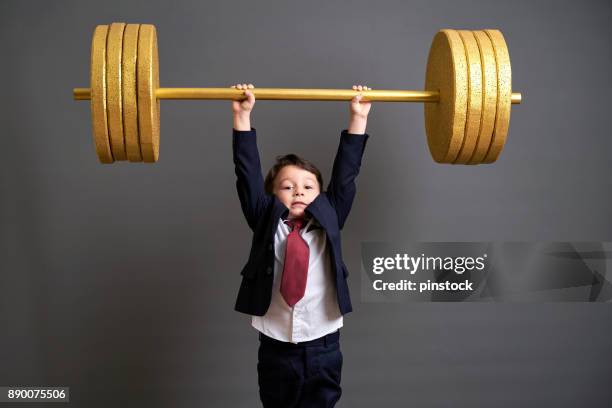 cute business boy lifting gold barbell - young kid and barbell stock pictures, royalty-free photos & images