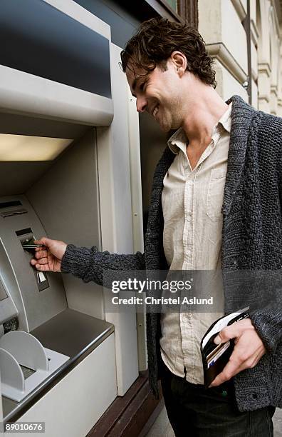 man at cash dispenser - man atm smile stock pictures, royalty-free photos & images