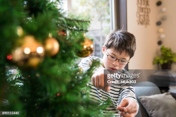 A boy with Downs syndrome decorates a Christmas tree