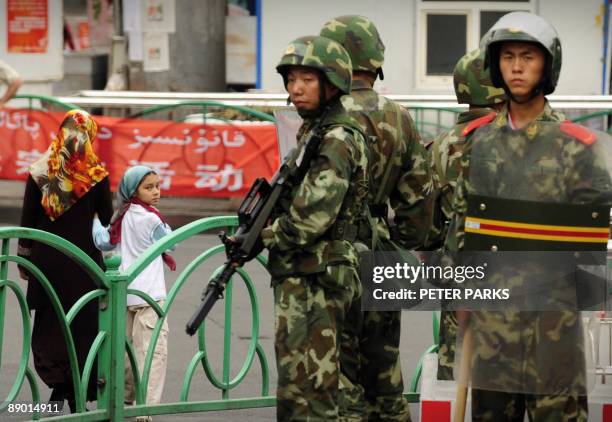 Chinese paramilitary policemen stand guard on a street in the Uighur district of Urumqi city, in China's Xinjiang region, on July 14, 2009. A mosque...