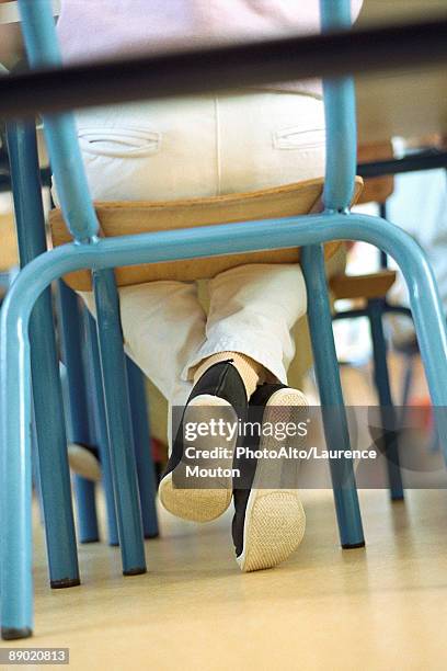 child sitting in chair, legs crossed at ankle, low angle view - pés cruzados - fotografias e filmes do acervo