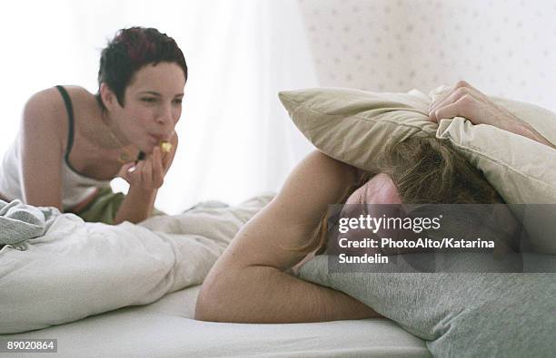 young woman blowing whistle, awakening sleeping young man - veralbern stock-fotos und bilder