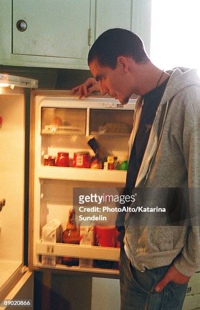 young man standing in front of open refrigerator  - open fridge ストックフォトと画像