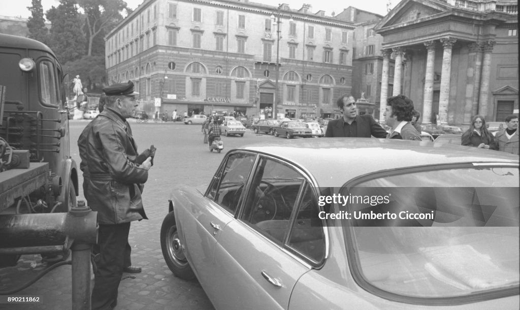 Adriano Celentano with the traffic policemen while they take away the car parked in a no parking area, Rome 1976