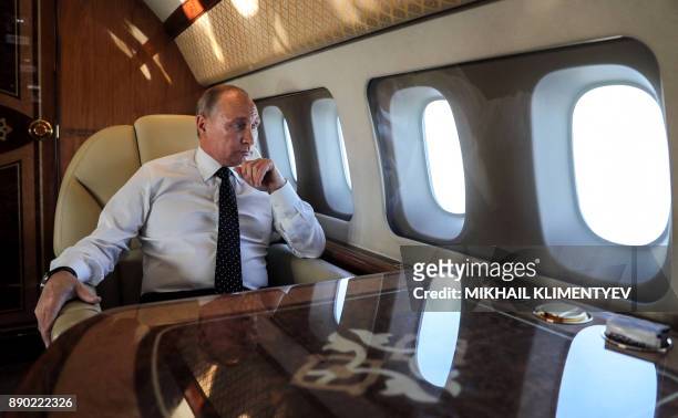 Russian President Vladimir Putin looks through the porthole while aboard the presidential plane during the approach to the Russian air base in...