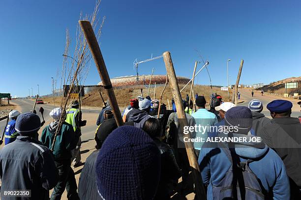 Striking South African construction workers, brandishing sticks and singing, demonstrate around City Stadium in Soweto on July 14, 2009. National...