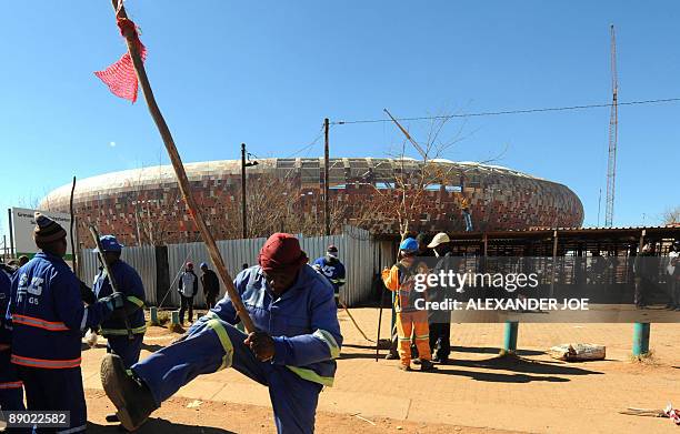Striking South African construction workers, brandishing sticks and singing, demonstrate around City Stadium in Soweto on July 14, 2009. National...