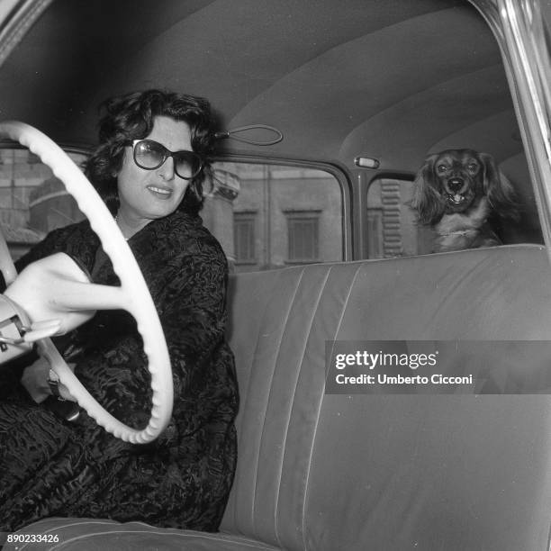 Italian stage and film actress Anna Magnani in a car with her dog, Rome 1957.