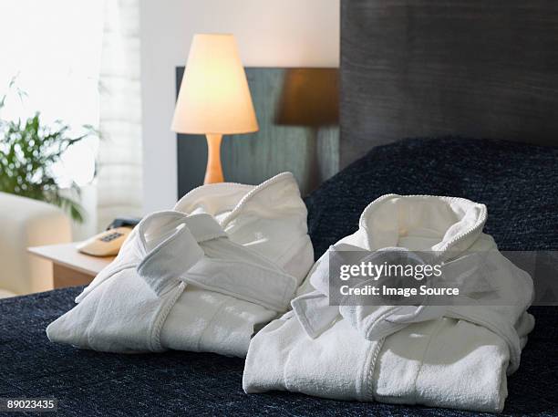 folded bathrobes on a hotel bed - bademantel stock-fotos und bilder