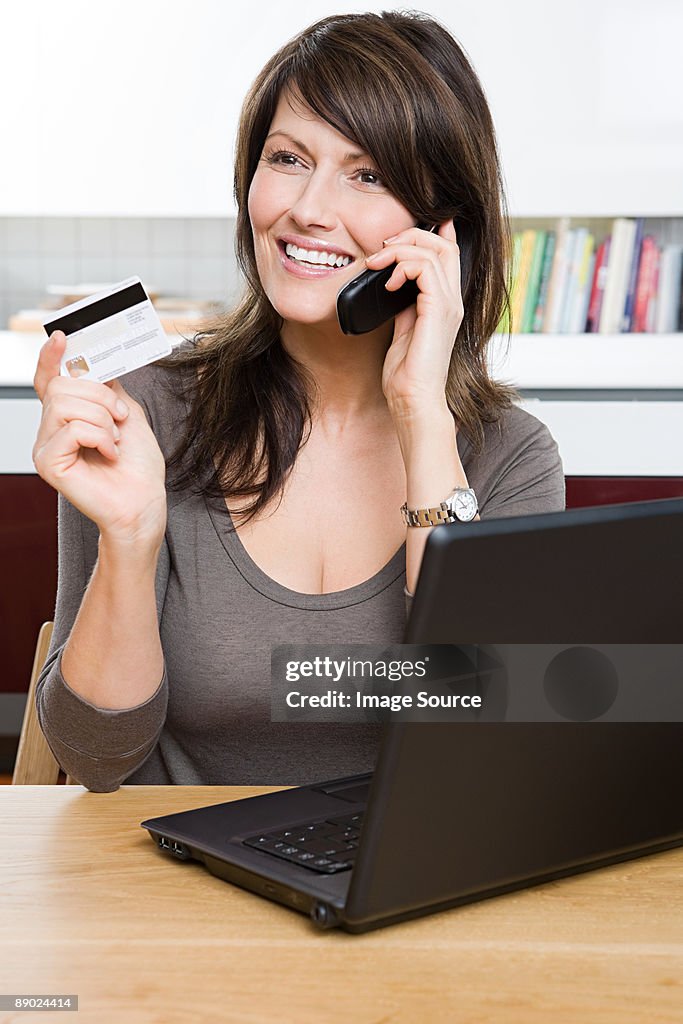 Woman with cellphone credit card and laptop