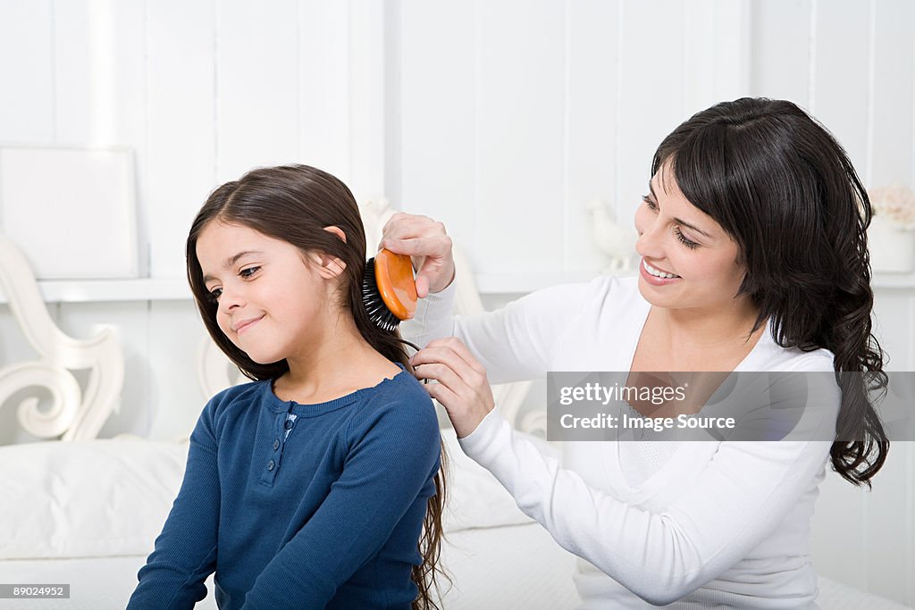 Mother combing daughters hair