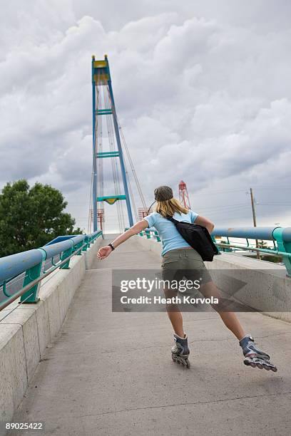 woman inline skating over pedestrian bridge. - footbridge stock pictures, royalty-free photos & images