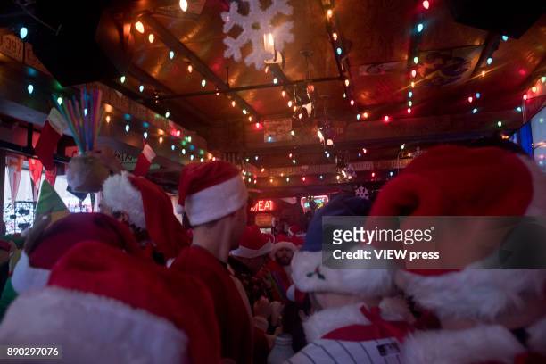 People dressed as a Santas drink at a bar in Manhattan during the annual SantaCon pub crawl on December 9, 2017 in New York City. Hundreds of...
