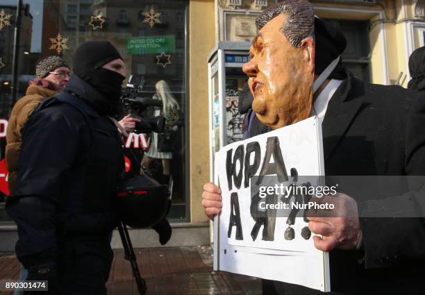 Protester wearing a mask of Ukrainian ex-president Yanukovych holds a placard which asks &quot;What about my, Yura?&quot; during a protest in front...