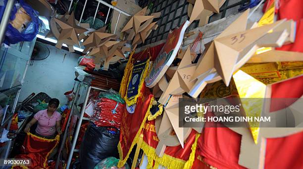 Woman sorts stuff out inside her tinny shop selling political decorative items including flags, banners, communist signs and portraits of Karl...