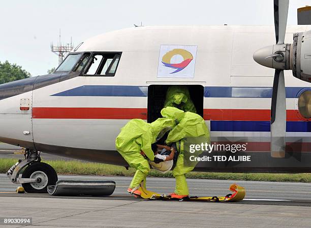 Fire-fighters wearing protective suits carry a person posing as an injured passenger from an aircraft during a Crash and Rescue Exercise at Manila...