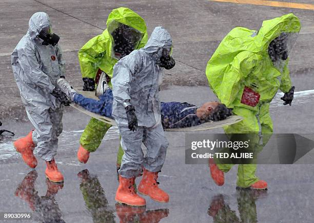 Fire-fighters wearing protective suits pull a stretcher carrying a person posing as an injured passenger away from an aircraft, during a Crash and...