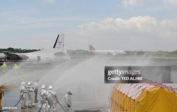 Fire-fighters spray Aqueous Film Forming Foam over people posing as injured passengers during a Crash and Rescue Exercise at Manila international...