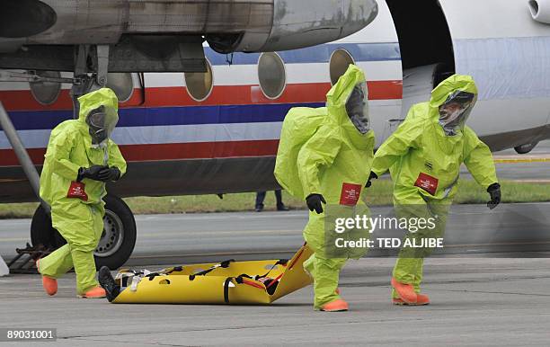 Fire-fighters wearing protective suits pull a stretcher carrying a person posing as an injured passenger away from an aircraft, during a Crash and...