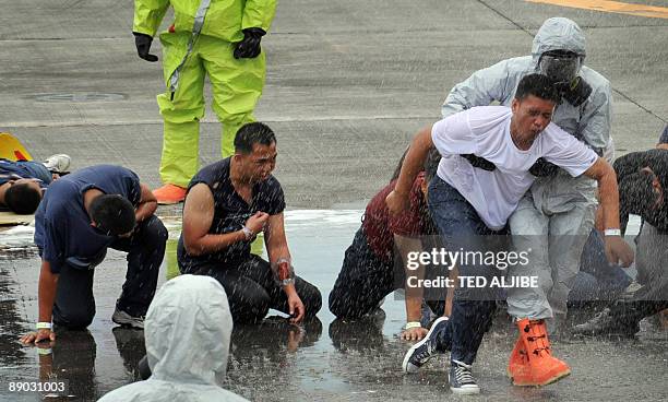 Fire-fighters wearing protective suits guide people posing as injured passengers during a Crash and Rescue Exercise at Manila international airport...