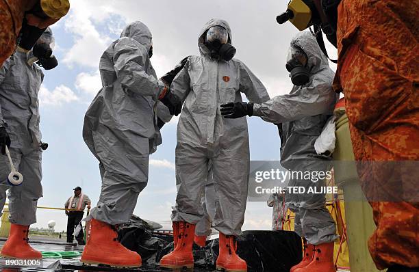 Fire-fighters wearing protective suits assist each other during a Crash and Rescue Exercise at Manila international airport on July 15, 2009. The...