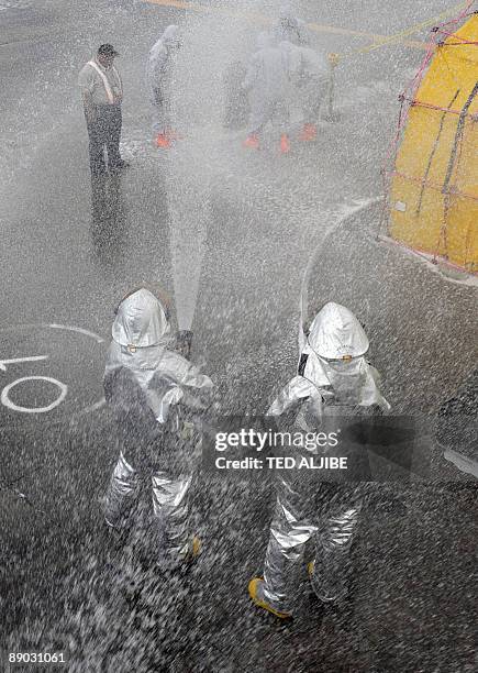 Fire-fighters spray Aqueous Film Forming Foam over people posing as injured passengers during a Crash and Rescue Exercise at Manila international...