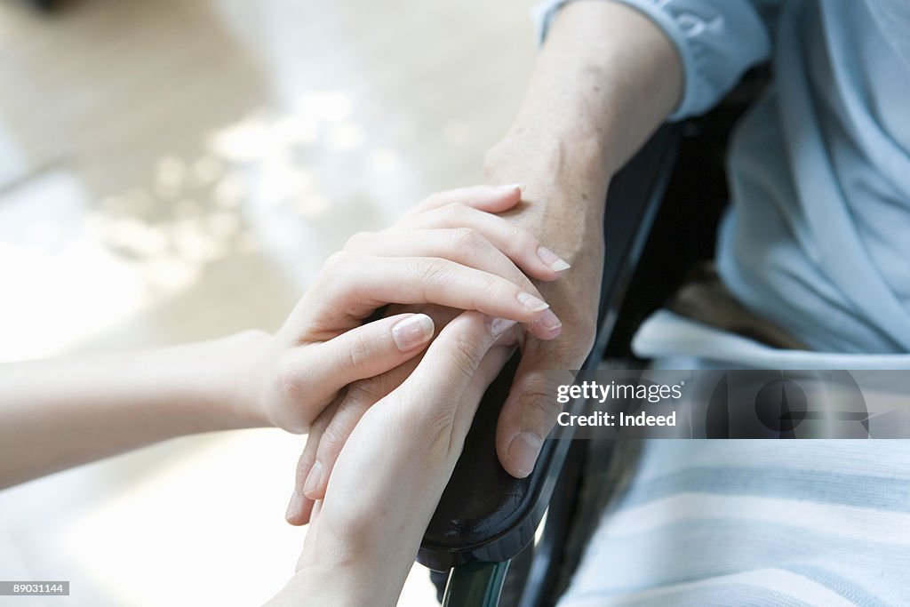 Woman holding hands of patient in wheelchair