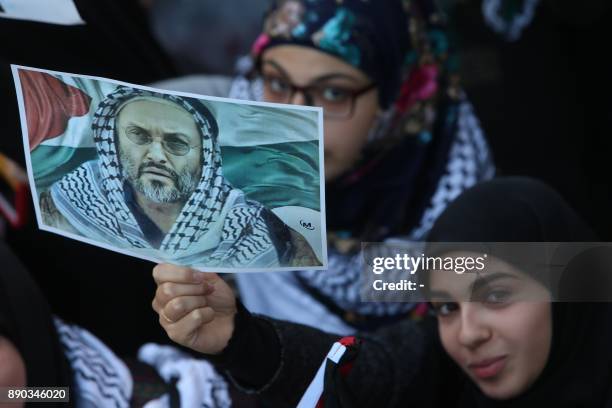 Lebanese Shiite protester, holds up a portrait of Hezbollah's slain former military commander Imad Mughniyeh, whose assassination in 2008 was blamed...