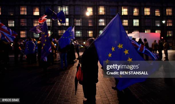Pro-EU protesters wave EU and Union Flags outside the Houses of Parliament in central London on December 11, 2017 as Britain's Prime Minister Theresa...