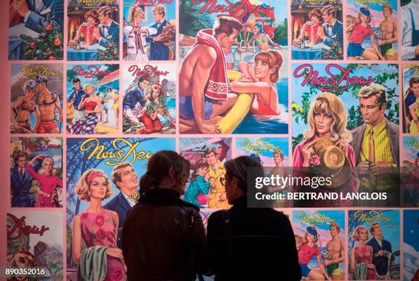 Women stand in front of cover pages of the photo novel 'Nous Deux' during a press preview of the exhibition 'Roman-Photo ' at the Museum of European...
