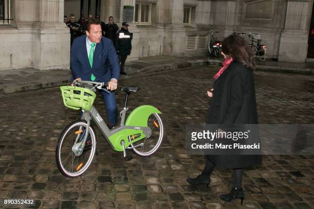 Former Governor of the US State of California Arnold Schwarzenegger rides a 'Velib' electric bicycle and is welcomed by the mayor of the city of...