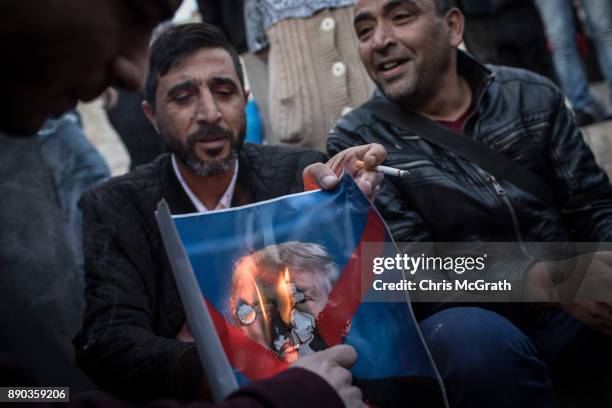 Protesters burn a poster of U.S. President Donald Trump in front of the Damascus Gate at the entrance to the Old City on December 11, 2017 in...