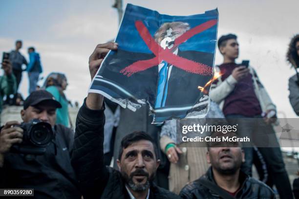 Protesters burn a poster of U.S. President Donald Trump in front of the Damascus Gate at the entrance to the Old City on December 11, 2017 in...