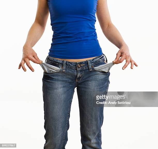 young woman holding out empty pockets - empty pockets stock pictures, royalty-free photos & images
